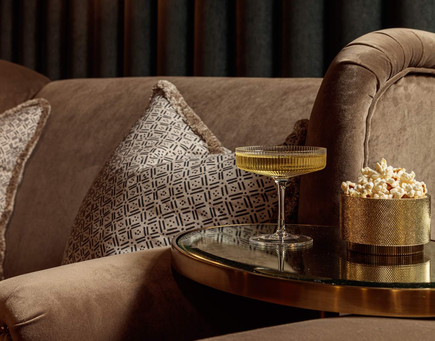 Close up of cocktail next to velvet sofa in cinema room