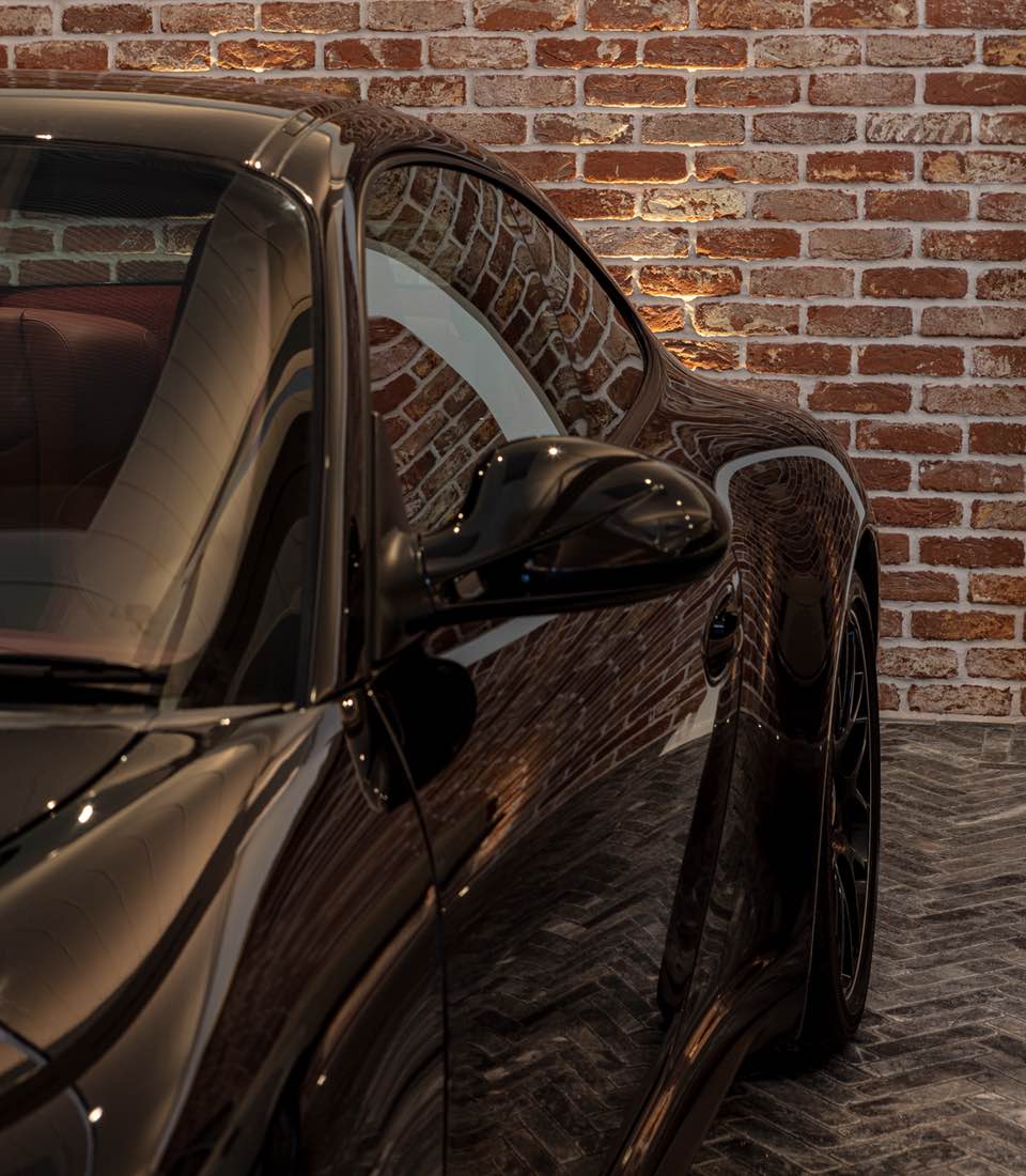 Garage with exposed brick wall, spotlights and classic cars