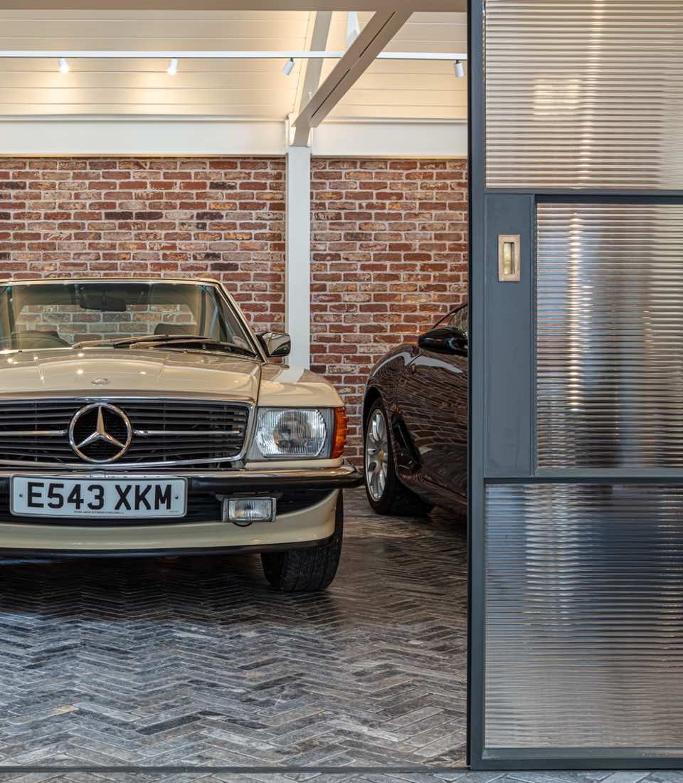 Garage with exposed brick wall, spotlights and classic cars