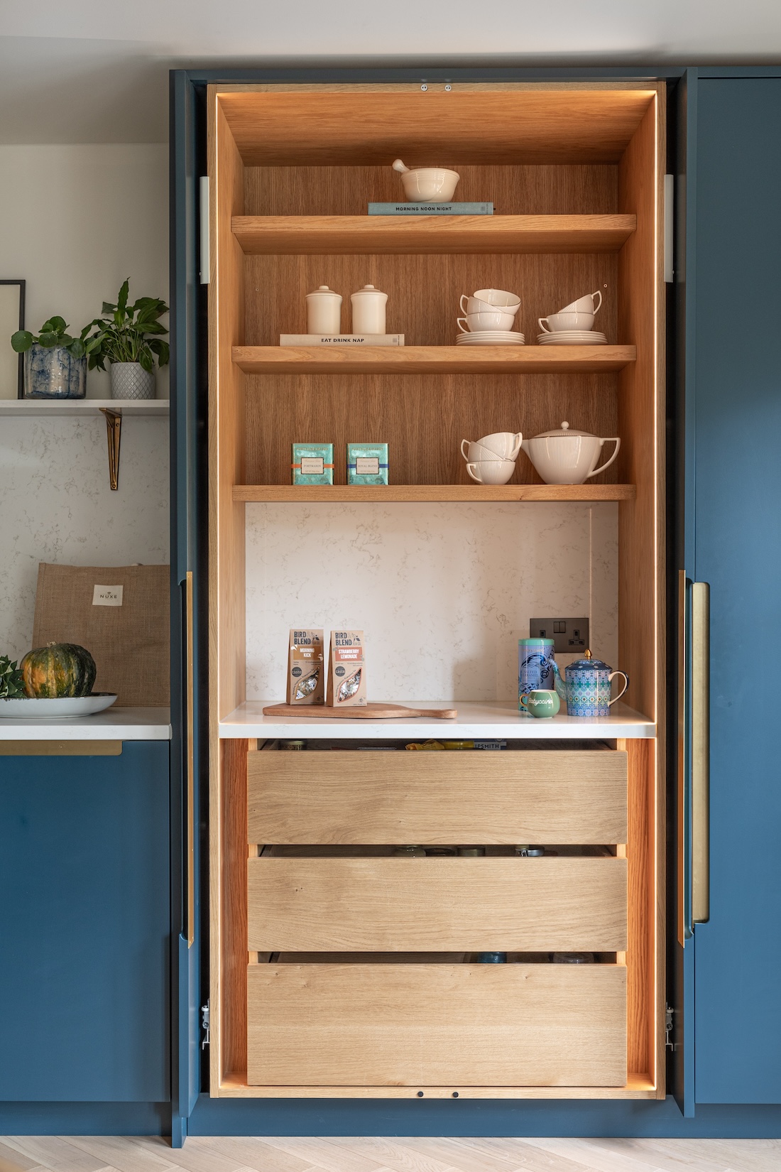 Art Deco Inspired Bespoke Kitchen made by our bespoke joiners, designed by Pfeiffer Design. Breakfast cabinet with pocket system sliding doors, handy drawers and shelving for easy mornings, brass insert handles, light timber chevron flooring