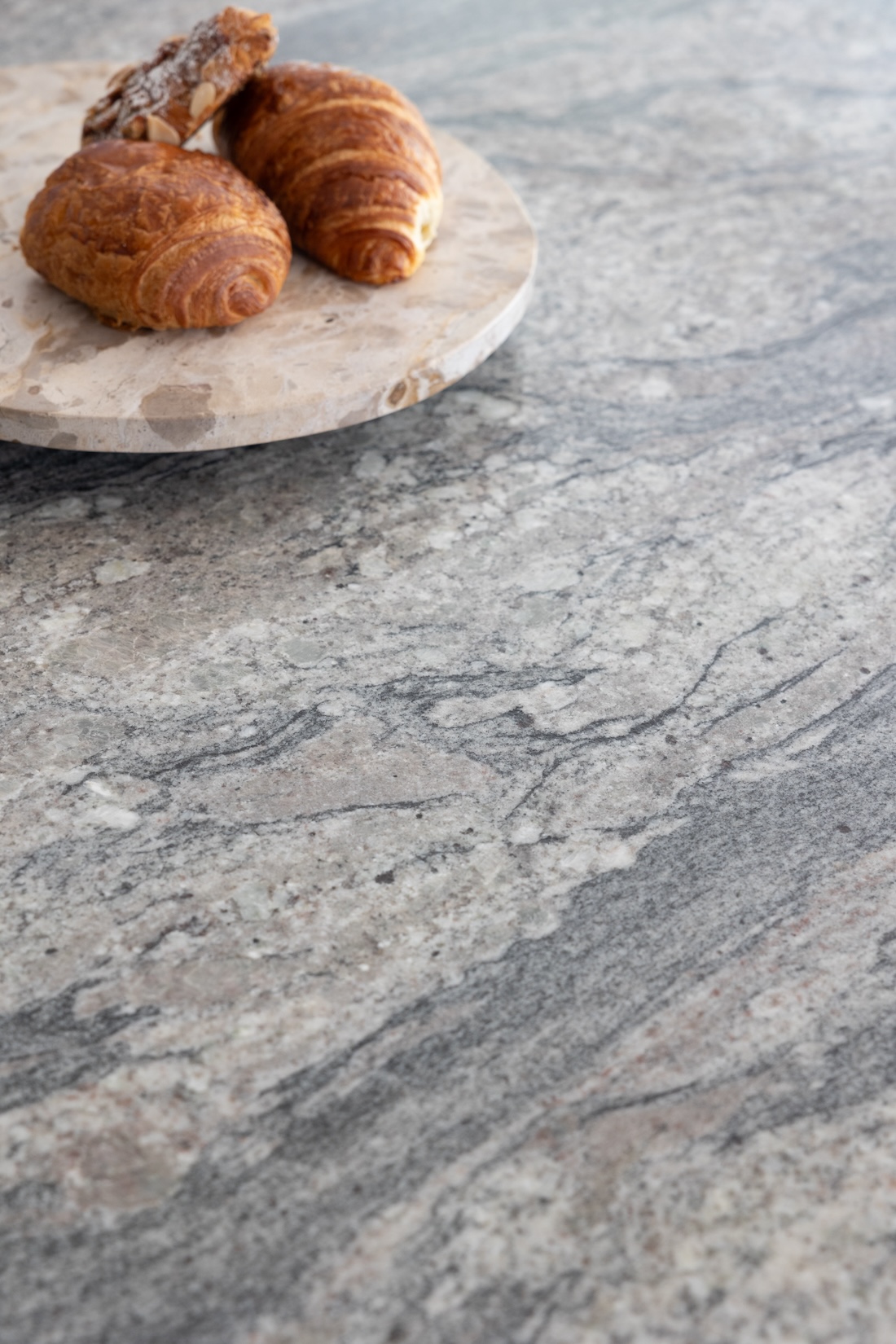 Art Deco Inspired Bespoke Kitchen made by our bespoke joiners, designed by Pfeiffer Design. Bespoke joinery, stone island work surface close up with breakfast pastries on a marble turntable platter